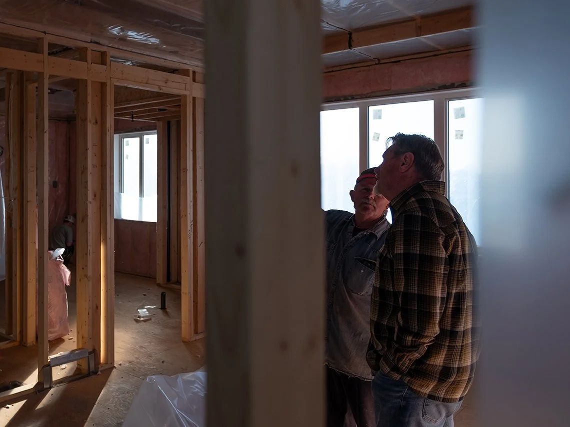 Two builders discussing framing inside a fully framed house