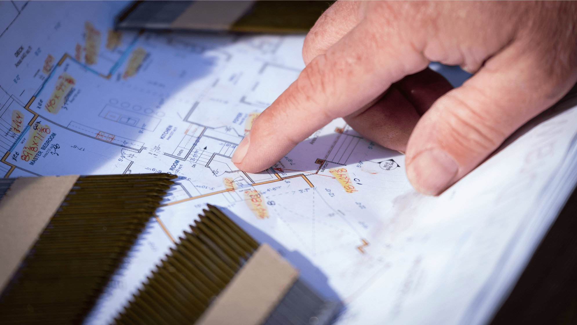 Image of a home construction plan with a finger pointing to a location on the plan