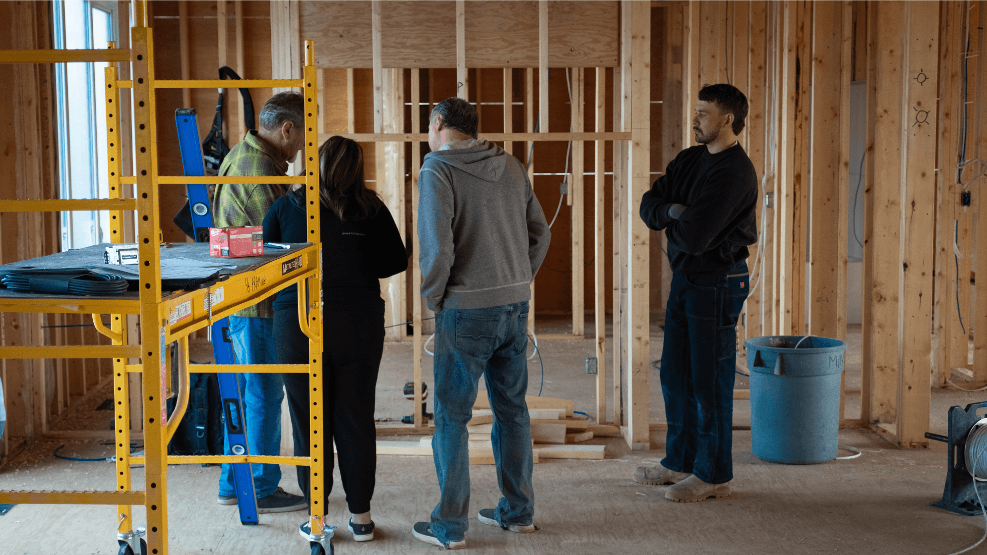Group of four people having a discussion inside a new build home at the framing stage