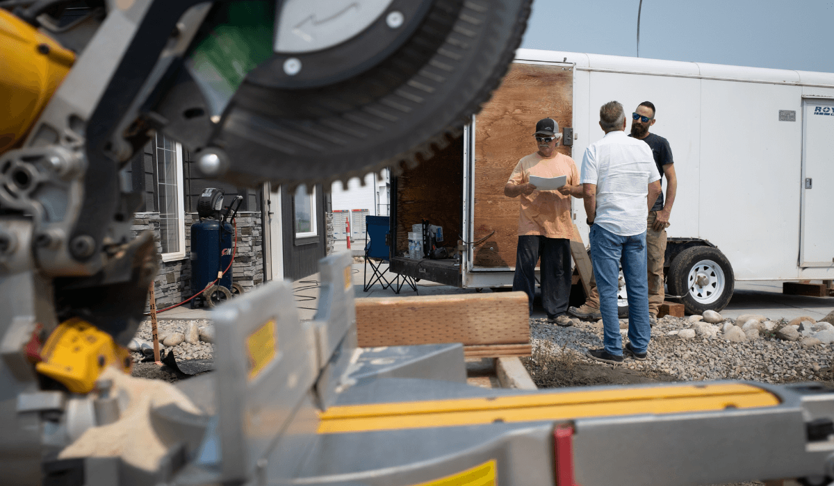 Three men standing outside a new home construction having a conversation