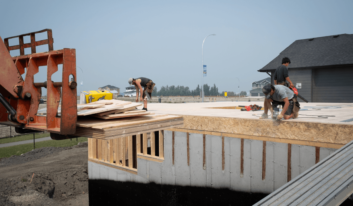 Three men standing outside a new home construction having a discussion